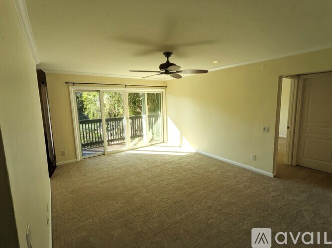 A room with a ceiling fan and a sliding glass door leading to a deck.