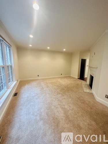A spacious room with beige carpeting and a fireplace.