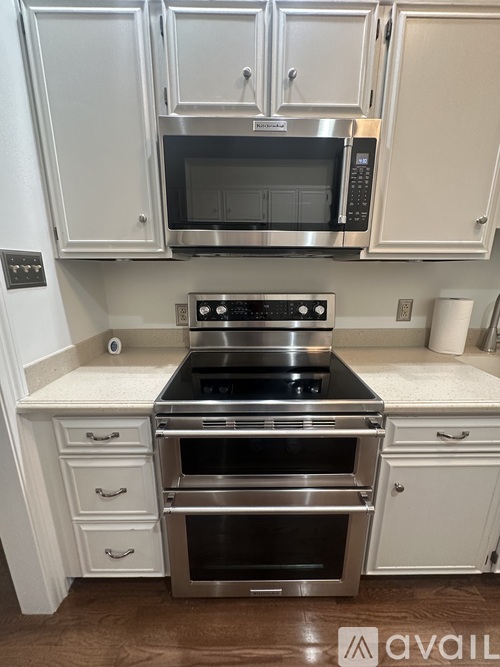 A kitchen with white cabinets and a stainless steel oven.
