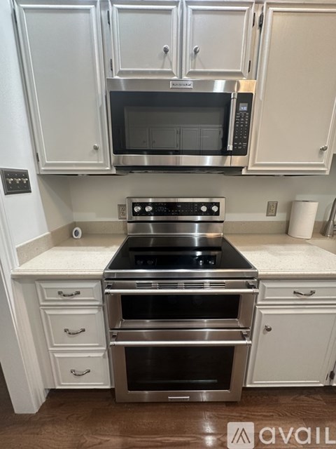 A kitchen with white cabinets and a stainless steel oven.