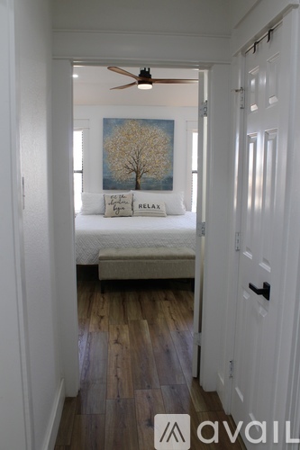 A bedroom with a bed and a painting of a tree on the wall.
