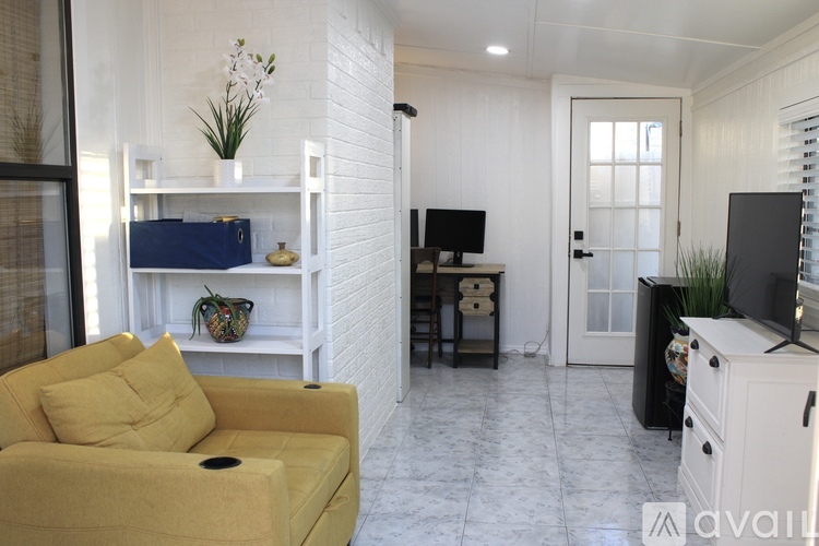 A living room with a yellow sofa and a white brick wall.