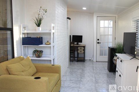 A living room with a yellow sofa and a white brick wall.