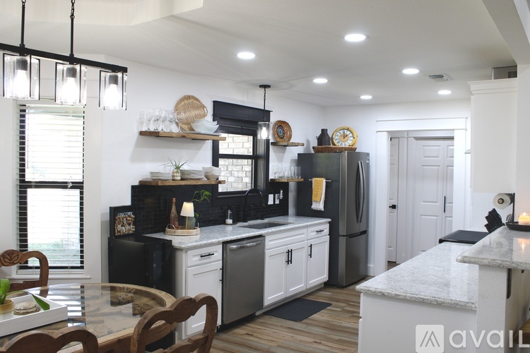 A modern kitchen with a glass table and stainless steel appliances.