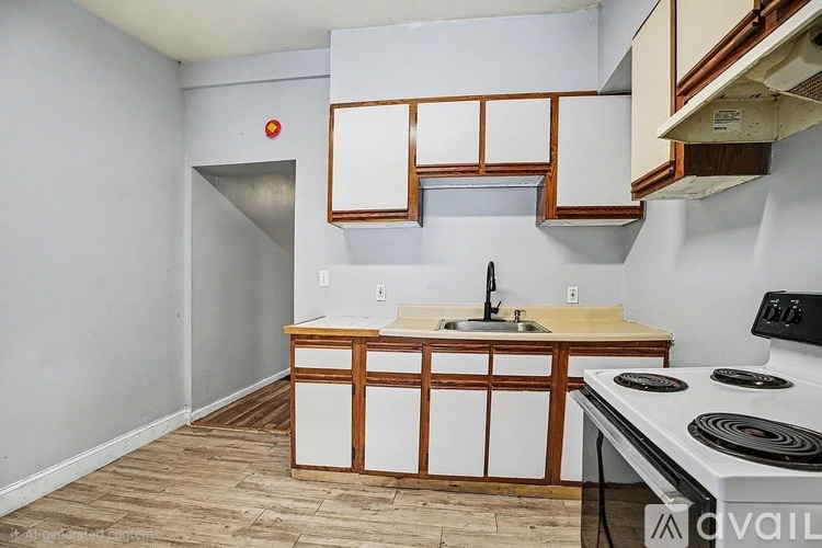 A kitchen with a white stove top oven and wooden cabinets.