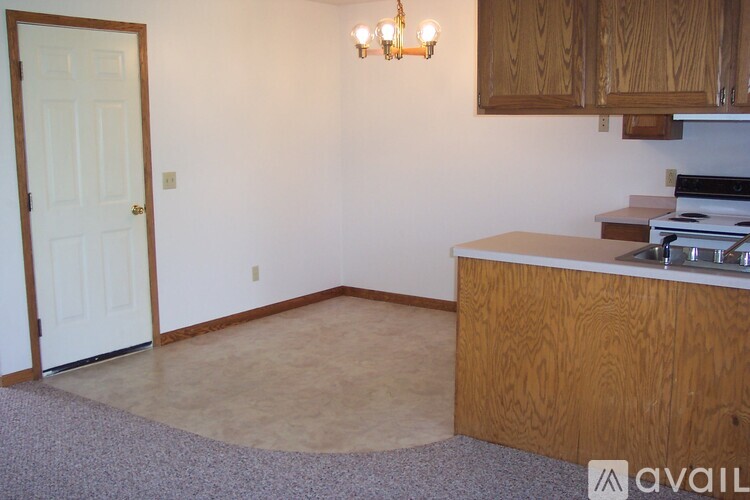 A kitchen with a white door and wooden cabinets.