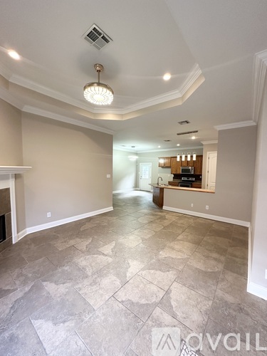 A spacious living room with a stone floor and a chandelier hanging from the ceiling.