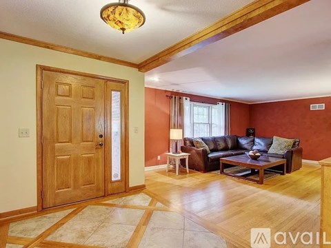 A living room with a brown leather couch and a wooden door.