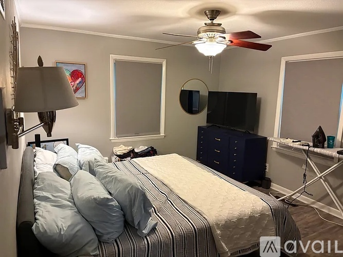 A bedroom with a bed, dresser, and a ceiling fan.