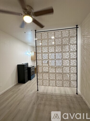 A room with a patterned screen door and a ceiling fan.