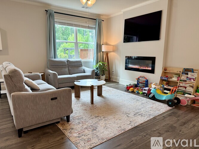 A living room with a grey couch, a coffee table, a television, and a fireplace.
