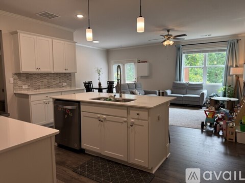A kitchen with white cabinets and a black and white checkered floor mat.
