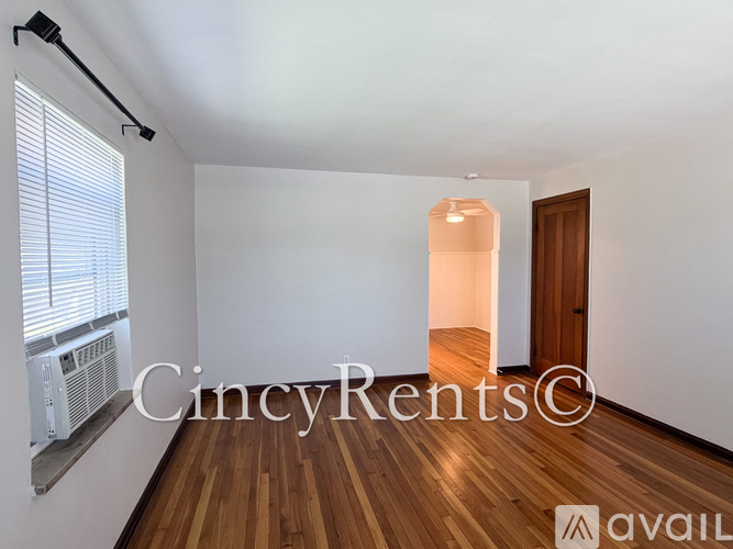 A room with wooden floors and white walls, with a window on the left side.