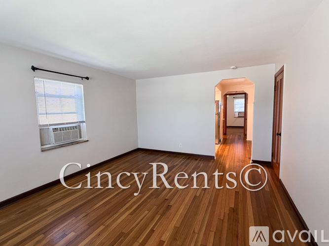 A room with wooden floors and a window with blinds.
