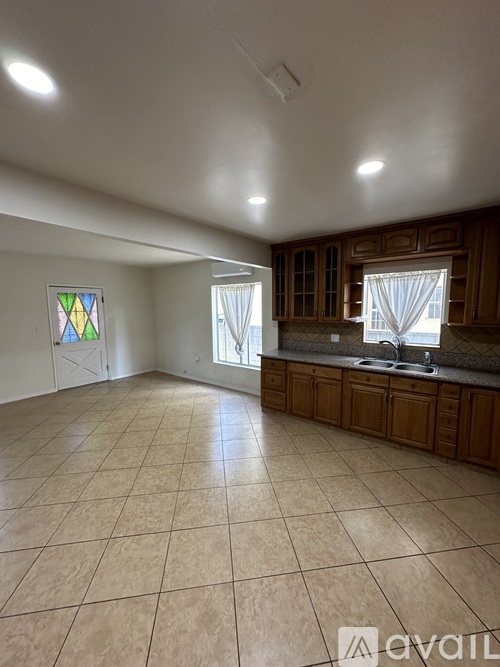 A kitchen with wooden cabinets and a tiled floor.