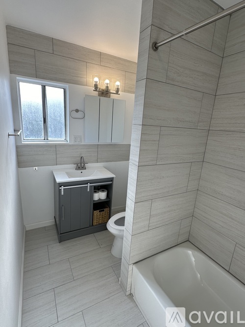 A bathroom with a tub, sink, and a window.