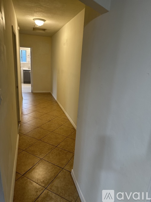 A long hallway with tiled floors and white walls.