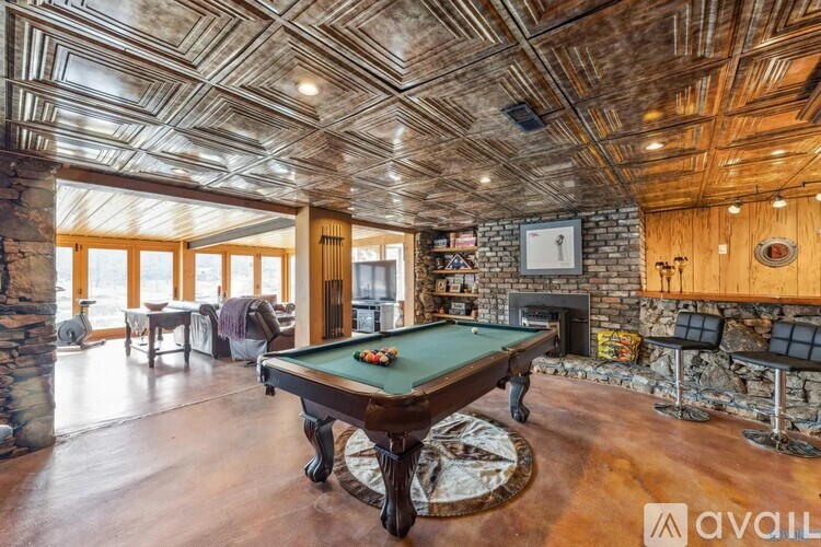 A pool table in a room with wooden floors and a stone fireplace.