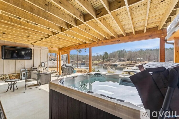 A wooden covered patio with a hot tub and a television.