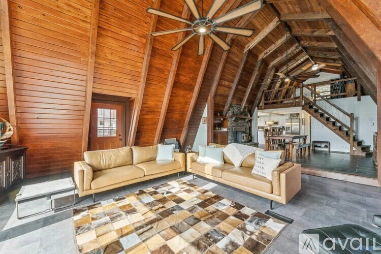 A living room with a tan couch and a wooden ceiling.