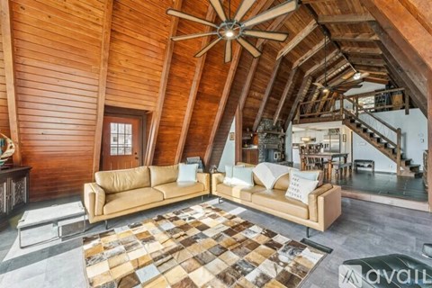 A living room with a tan couch and a wooden ceiling.