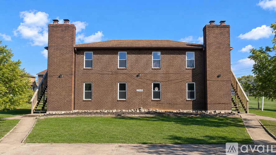 A large brick building with a green lawn in front.
