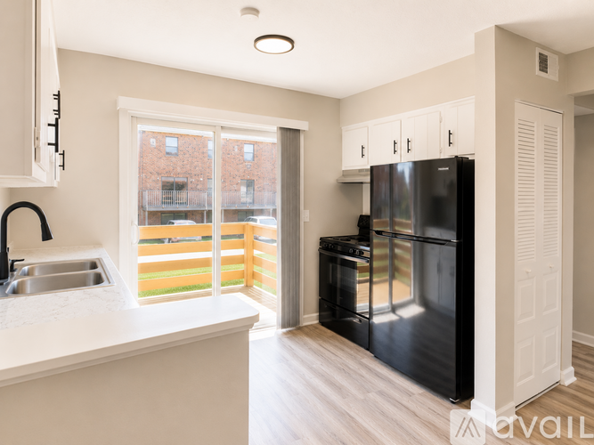 A kitchen with a black refrigerator and white cabinets.