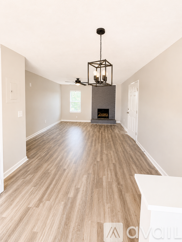 A wood floored room with a light hanging from the ceiling.