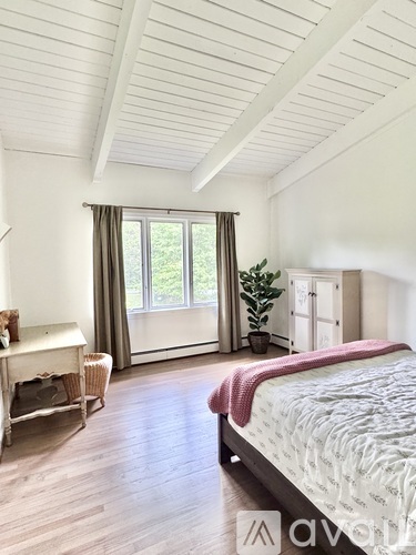 A bedroom with a large bed and a window with curtains.