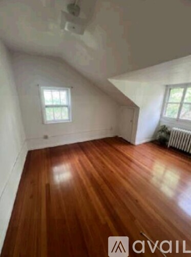 A room with wooden floors and two windows.