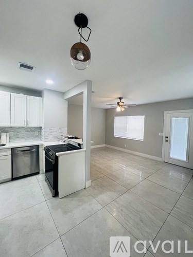 A kitchen with white cabinets and a black dishwasher.