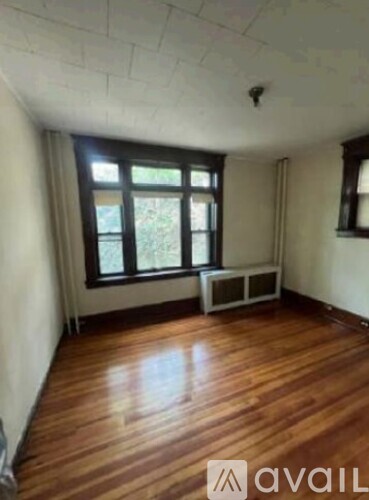 A room with wooden floors and a window with blinds.