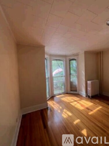 A room with wooden floors and a window overlooking a garden.