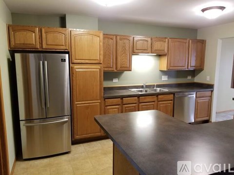 A kitchen with wooden cabinets and a stainless steel refrigerator.