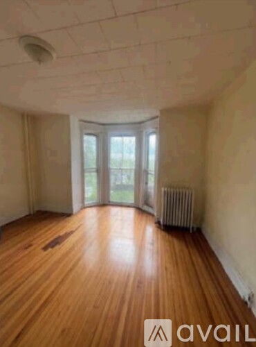 A room with wooden floors and a window with a view of trees.
