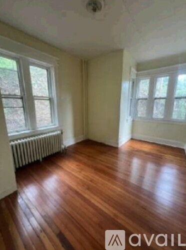 A room with wooden floors and two windows.