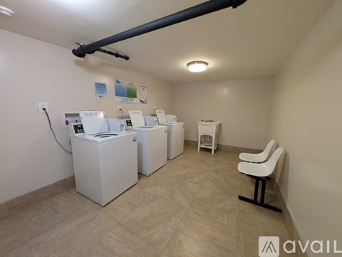 A room with a white chair and a white cabinet with a black pipe running along the ceiling.