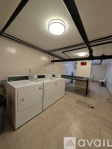 A room with white cabinets and a trash can.