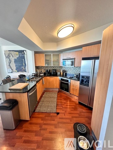 A kitchen with wooden floors and a refrigerator on the right.