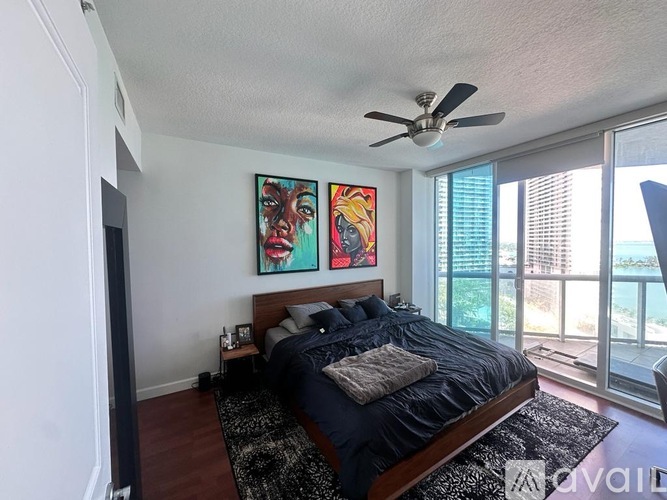 A bedroom with a bed, a ceiling fan, and two paintings on the wall.