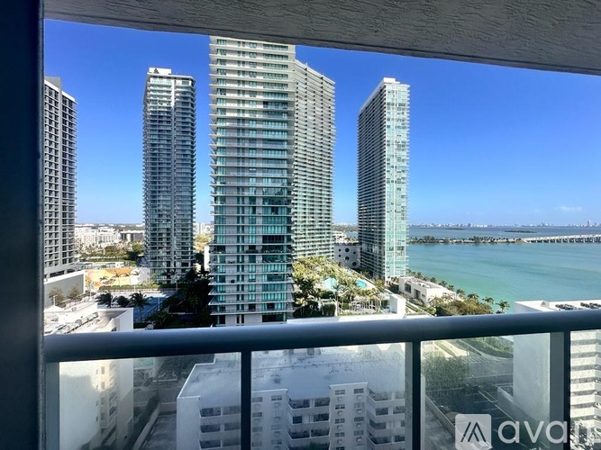 A view from a balcony overlooking a cityscape with tall buildings and a body of water.