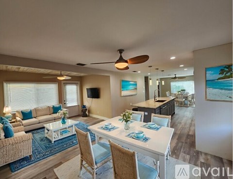 A well-lit living room with a dining area and a kitchen in the background.