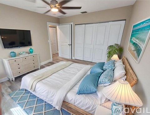 A bedroom with a large bed, a ceiling fan, and a television.