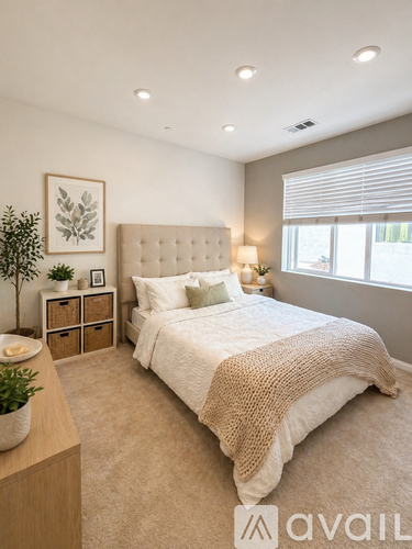 A bedroom with a large bed and a plant on the nightstand.