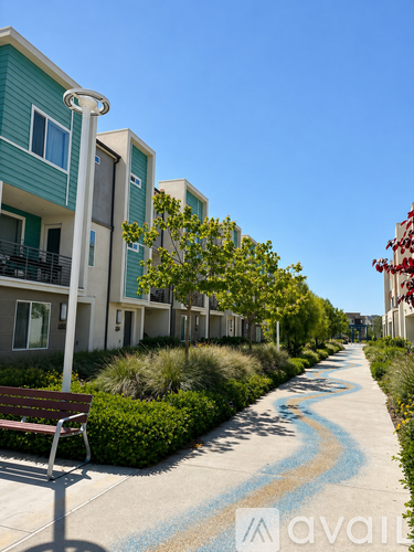 A long concrete path with a bench on the side and apartment buildings on the other side.