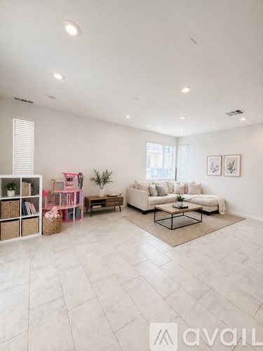 A living room with a white sofa set and a glass coffee table.