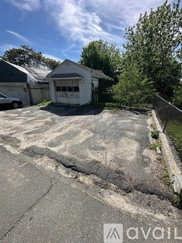 A white garage with a car parked in front of it.