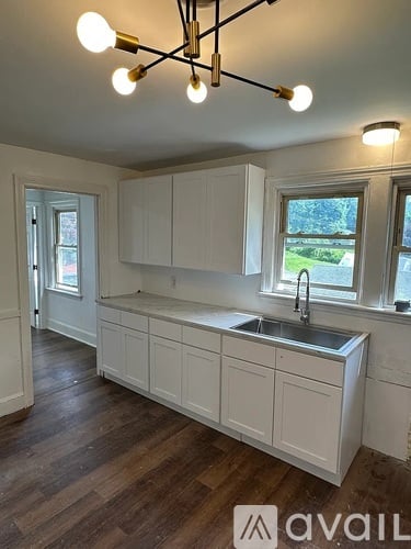 A kitchen with white cabinets and a sink under a window.
