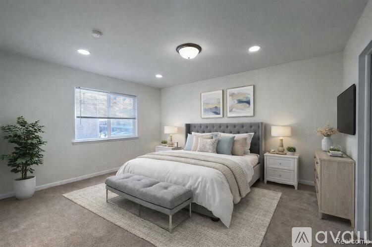 A well-lit bedroom with a large bed and a potted plant.