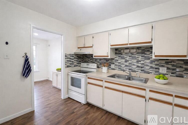 A kitchen with white cabinets and a stone backsplash.